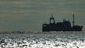 Big fishing boat trawling and catching fish as it crosses sea at horizon line during sunset. the fishing and sea-faring