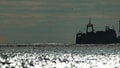 Big fishing boat trawling and catching fish as it crosses sea at horizon line during sunset. the fishing and sea-faring