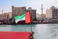 Big flag of United Arab Emirates flying high on city of Dubai in old town. Natoinal Day UAE. Royalty Free Stock Photo