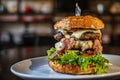 Big fresh and juicy beef burger with bacon on a black table in a restaurant, close-up Royalty Free Stock Photo