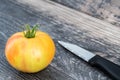 Big fresh yellow tomato with knife  on wood  background Royalty Free Stock Photo