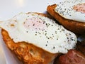 Big fried egg of English breakfast with sunny fried eggs, bacon, tomatos, ham on Turkish flat grilled bread on white dish