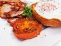 Big fried grilled tomato of English breakfast with sunny fried eggs, bacon, tomatoes, ham on Turkish flat grilled bread on white Royalty Free Stock Photo