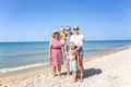 Big friendly family on the sandy seashore on a sunny day. Laughing grandmother, grandfather, mother and children. Leisure, travel