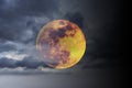 Big full yellow red moon in dark blue cloudy sky over some clouds. Royalty Free Stock Photo