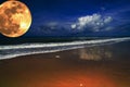 Big full yellow moon in dark blue cloudy sky over the sea / ocean. Empty beach. Planet close to the Earth. Royalty Free Stock Photo