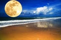 Big full yellow moon in dark blue cloudy sky over the sea / ocean. Empty beach. Planet close to the Earth. Royalty Free Stock Photo