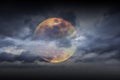 Big full yellow red moon in dark blue cloudy sky over some clouds. Royalty Free Stock Photo