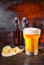 Big glass of freshly poured light beer against two beer bottles Royalty Free Stock Photo