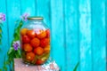 Big glass jar with pickled vegetables on chair on background of old wooden house. Canned tomatoes and cucumbers in Royalty Free Stock Photo