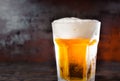Big glass with a light beer and a head of foam on old dark desk Royalty Free Stock Photo