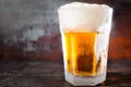 Big glass with a light beer and a large head of foam on old dark Royalty Free Stock Photo