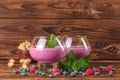 Big glasses with cocktails on a wooden background. Appetizing milkshake with blueberries, mint and peanuts. Copy space. Royalty Free Stock Photo