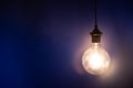 Big glowing light bulb against blue wall. Royalty Free Stock Photo