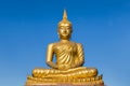 Big golden buddha statue sitting on blue sky background