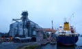 Big grain terminal at seaport. Cereals bulk transshipment from road transport to vessel. Loading grain crops on ship Royalty Free Stock Photo