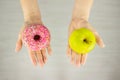 Big green apple and pink doughnut in hand. The concept of diet comparison Royalty Free Stock Photo