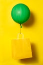Big green ballon holding yellow package for delivery on yellow background