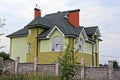 Big green house behind a gray brick fence in the grass Royalty Free Stock Photo