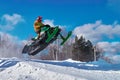 Big green Sport snowmobile jump. Cloud of snow dust from under snowmobile tracks.