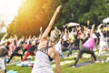 Big group of adults attending a yoga class outside in park