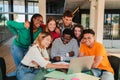 Big group of real teenage students searching information together using a laptop at university campus library Royalty Free Stock Photo