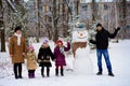 Big happy family: father, daughters and grandmother sculpt a big real snowman