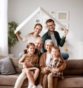 Big happy family sitting on the sofa under paper roof and smiling at camera Royalty Free Stock Photo
