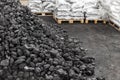 Big heap of dark black lump coal on floor bulk. Charcoal sorage at warehouse stock reserve. activated anthracite packed