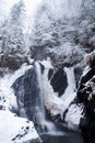 Big high Waterfall in the mountain winter forest with snow-covered trees and snowfall Royalty Free Stock Photo