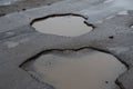 Big holes with puddle in asphalt road