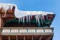 Big icicles and snow hanging over the rain gutter on a roof of a traditional wooden house in the mountains in winter. Royalty Free Stock Photo