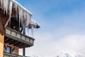 Big icicles and snow hanging over the rain gutter on a roof of a traditional wooden house in the mountains in winter. Royalty Free Stock Photo