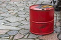 Big iron old red barrel can pour gasoline diesel oil, industrial object on a grey street stone tile road