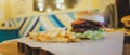 A big juicy burger with two cutlets, vegetables, sauce and french fries on the table in a cafe.