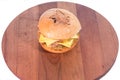 Big juicy double burger on a wooden plate on a table in a restaurant.