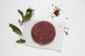 Big juicy homemade hamburger. Raw minced meat, a branch with bay leaves, coarse salt, pepper and spices on a light background Royalty Free Stock Photo