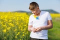 Teenage guy in T-shirt with Ukrainian flowers on it enjoys sun while standing in rapeseed field against clear sky Royalty Free Stock Photo