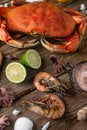 Big king crab, shrimps, octopuses served with lime, sea salt and seashells on wooden background. Close-up. Vertical format.