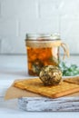 Big labne ball with herbs and spices on a background of a glass jar on a white table.