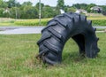 Big large black old tractor tire half buried in the grass Royalty Free Stock Photo