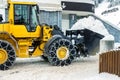 Big loader machine with steel metal chains removing big snow pile from city street at alpine mountain region in winter. Heavy Royalty Free Stock Photo