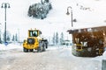 Big loader machine with steel metal chains removing big snow pile from city street at alpine mountain region in winter. Heavy