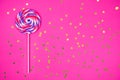 Big lollipop on solid pink background with golden sprinkles