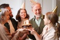 Big lovely caucasian family in party hats congratulating happy senior grandfather with his birthday Royalty Free Stock Photo