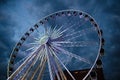 Big luminous ferris wheel in front of dark blue dramatic sky