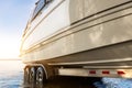 Big luxury cabin motorboat cruiser yacht launching at trailer ramp on river or lake. Warm morning sunrise sunshine Royalty Free Stock Photo