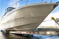 Big luxury cabin motorboat cruiser yacht launching at trailer ramp on river or lake. Warm morning sunrise sunshine Royalty Free Stock Photo