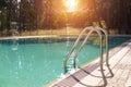 Big luxury empty rectangular swimming pool with clean blue water and ladder at tropical forest beach resort at sunrise morning Royalty Free Stock Photo