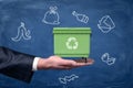 Big male hand holding green garbage bin on blue cartoon trash background Royalty Free Stock Photo